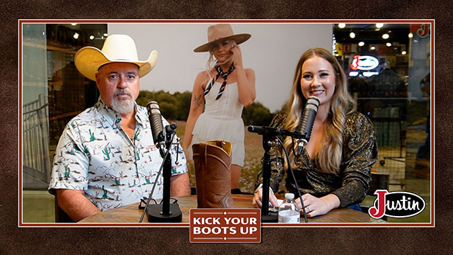 A woman with blonde hair and a man wearing a straw cowboy hat are sitting down beside each other, looking at the camera, smiling, sitting, and having a conversation.